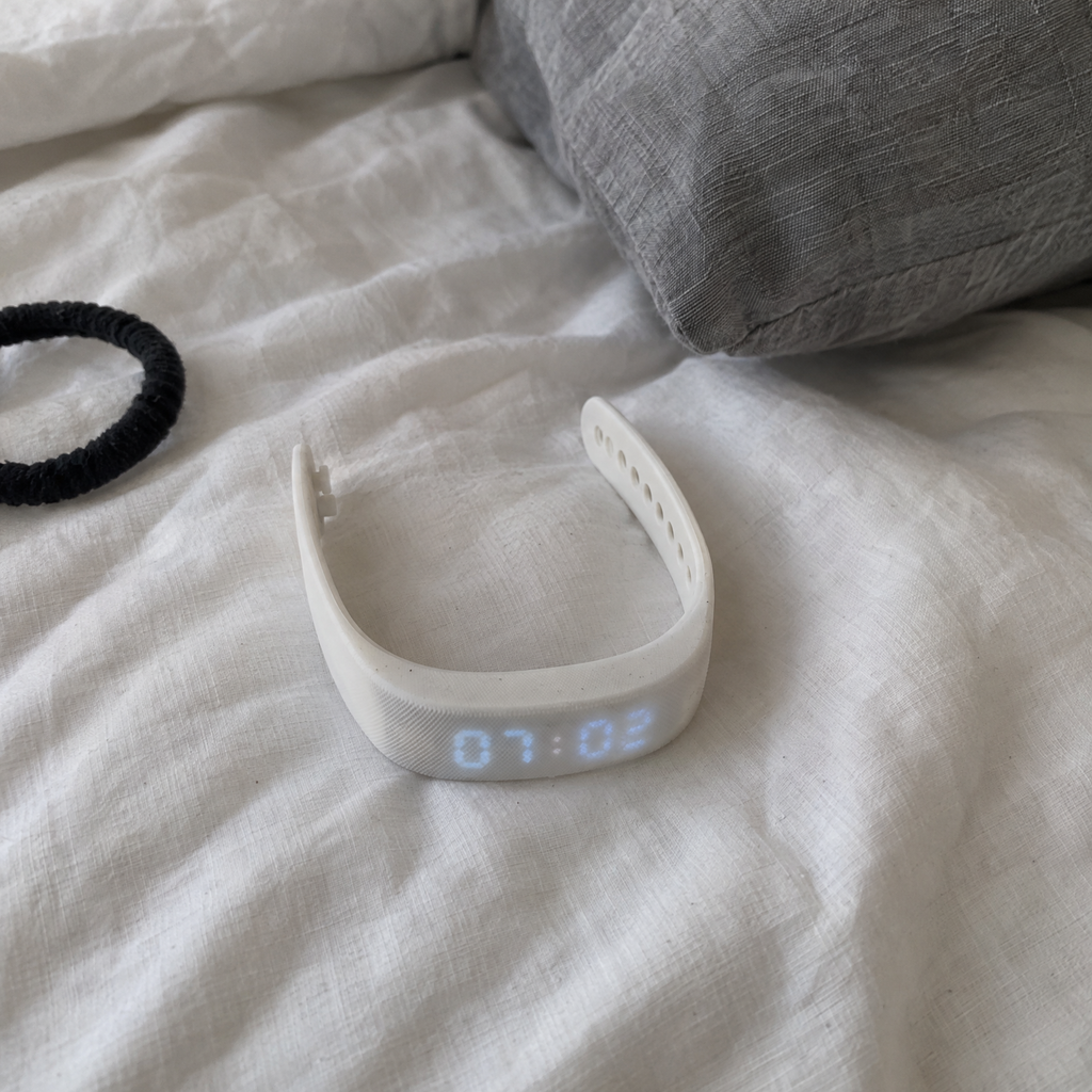 Nemi wristband on an unmade bed in the morning