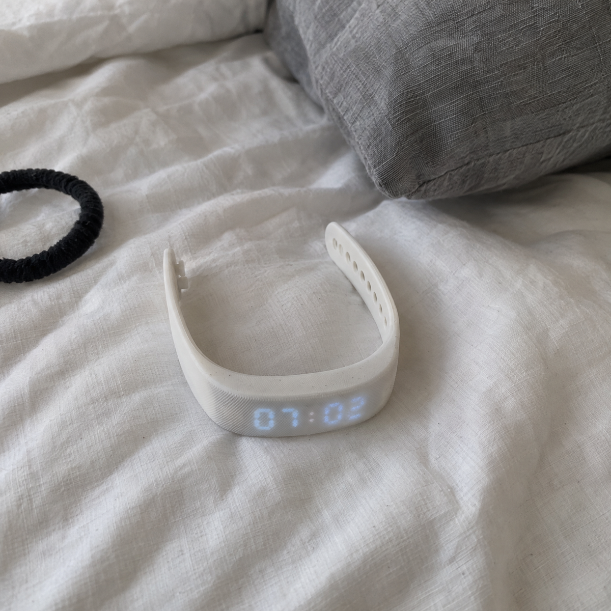 Nemi wristband on an unmade bed in the morning