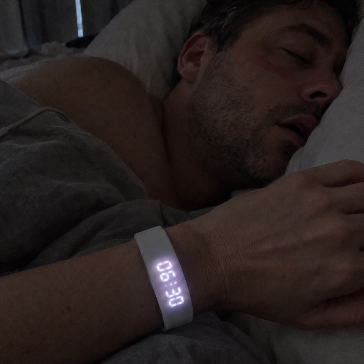 Woman checking the Nemi band at 6:30 a.m. while her partner sleeps on