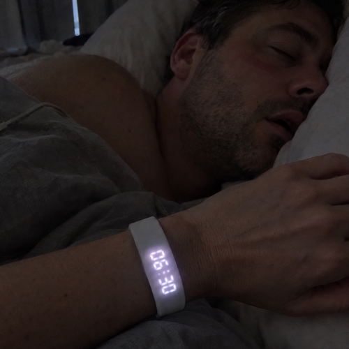 Woman checking the Nemi band at 6:30 a.m. while her partner sleeps on