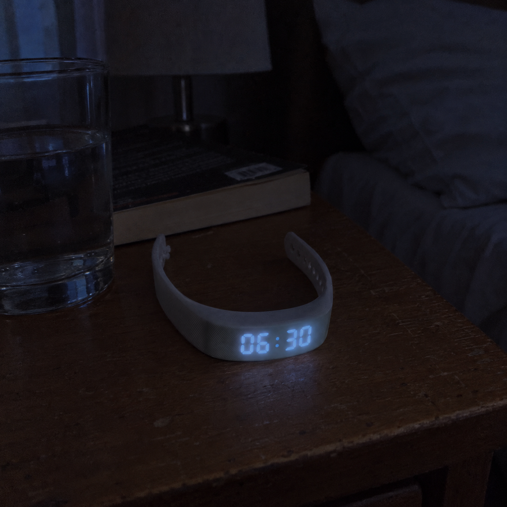 Nemi wristband on a nightstand at night, display showing 06:30