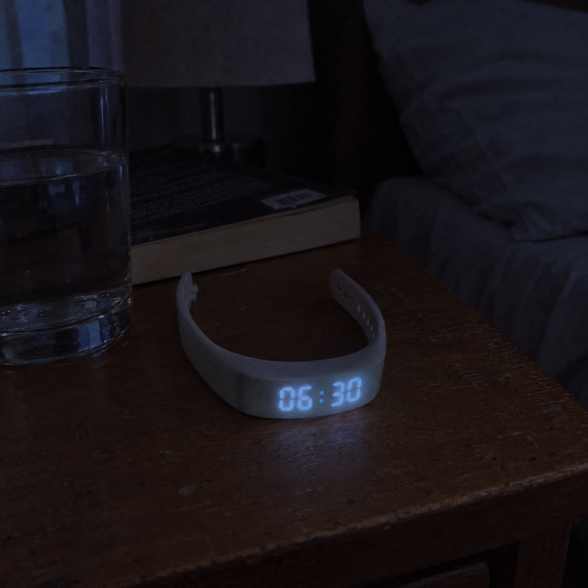 Nemi wristband on a nightstand at night, display showing 06:30