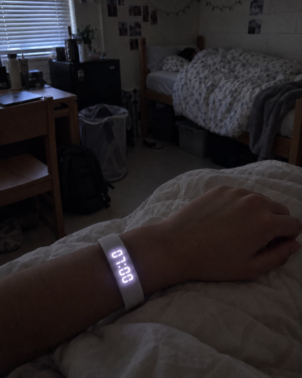 Student's wrist with the Nemi band while her roommate sleeps across the dorm room